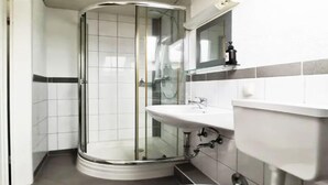 A modern bathroom with a glass shower enclosure, a white sink, and a toilet. - Apartment Hainstädter Straße (Hanau)