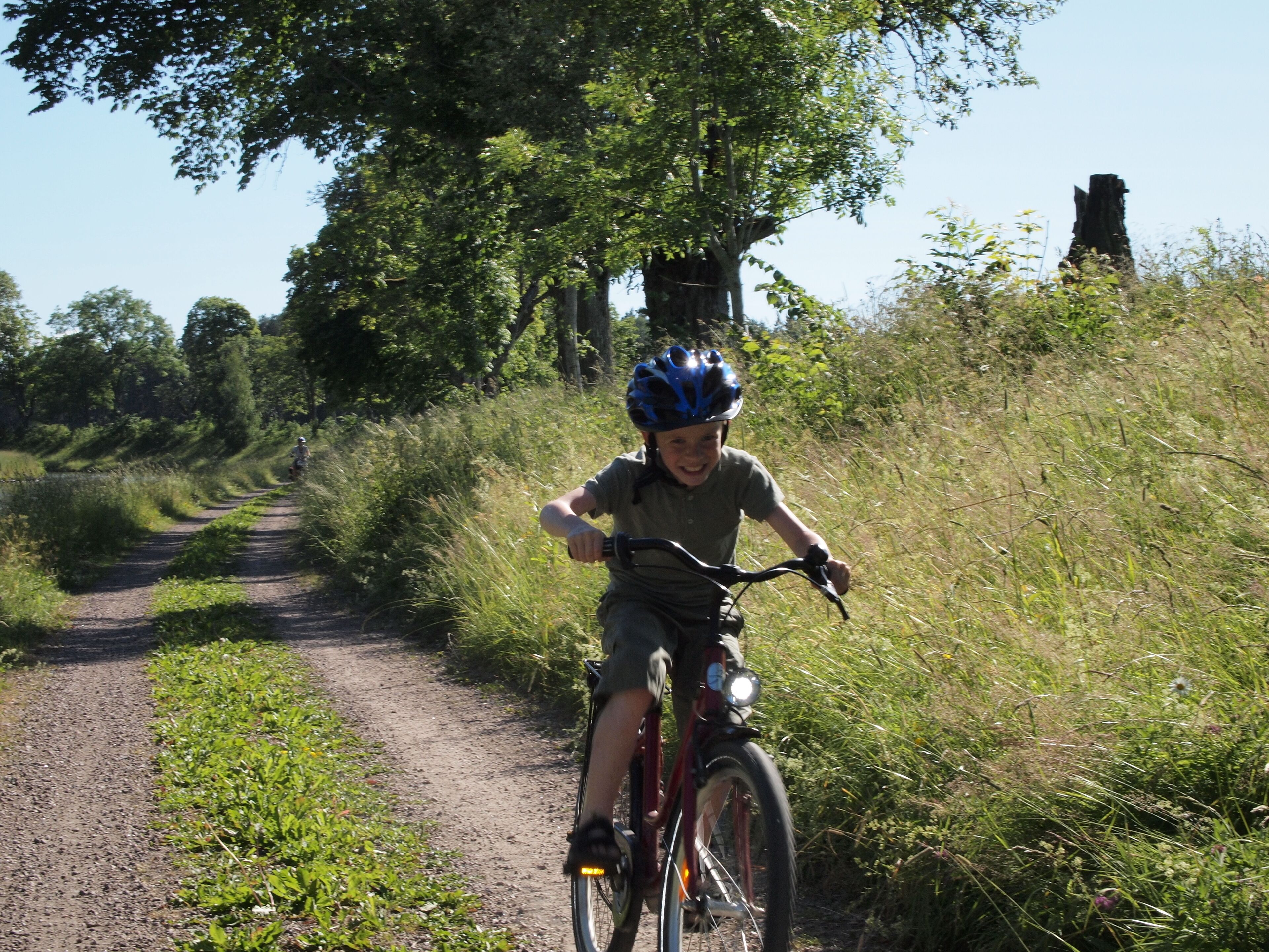 A person riding a bicycle on a dirt path surrounded by greenery.