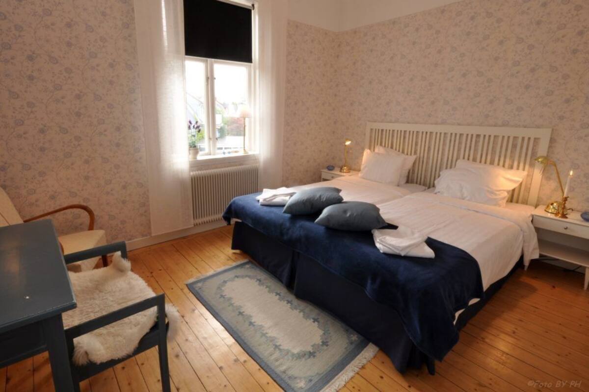 Ein Schlafzimmer mit einem großen Bett, einem Sessel, einem Schreibtisch und einem Fenster.