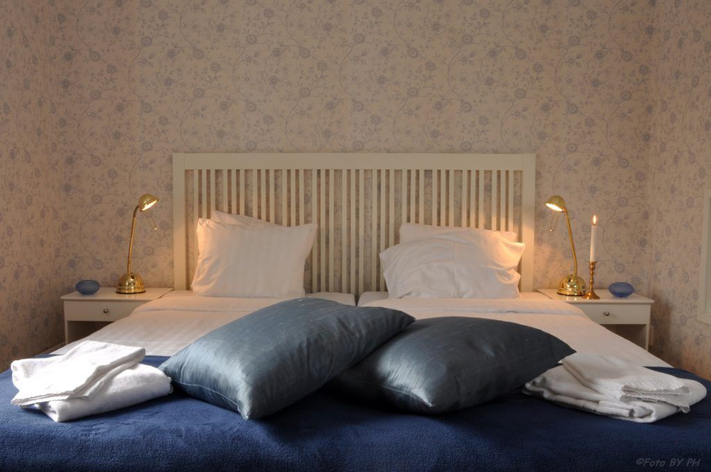 A neatly made bed with two pillows and two bedside lamps.