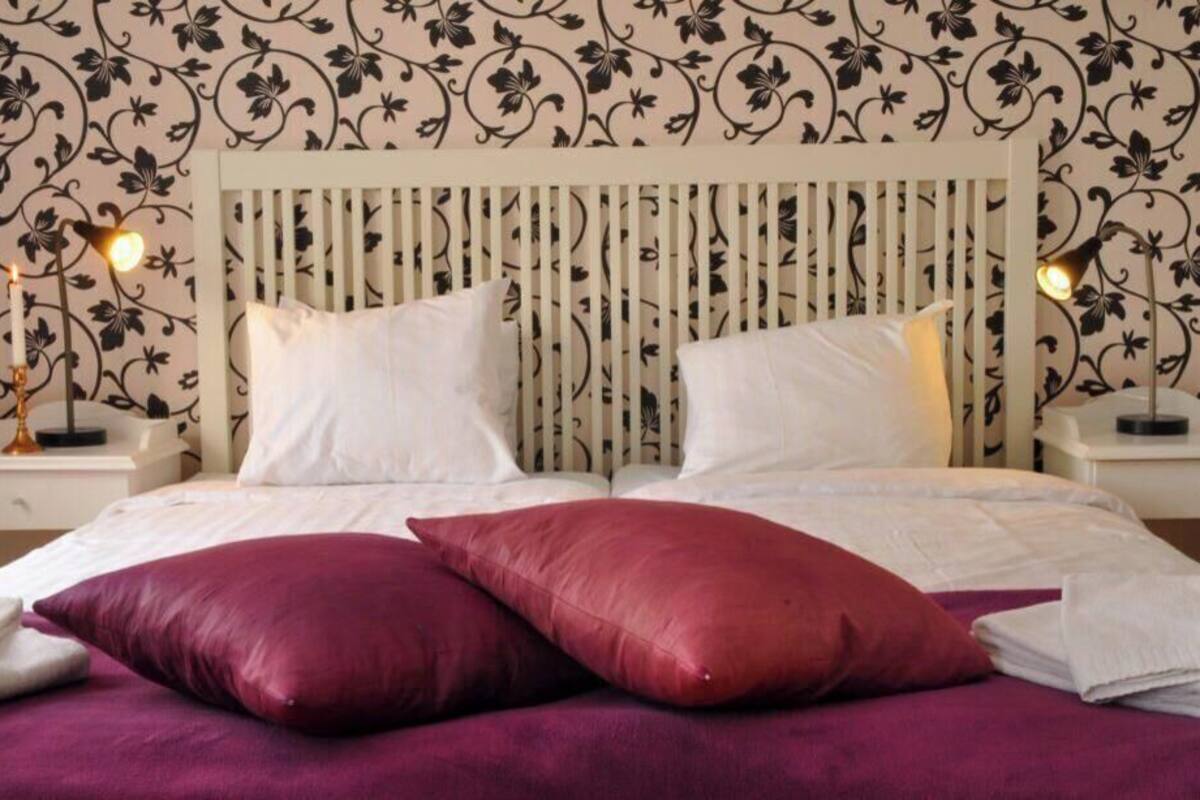 Ein Bett mit zwei weißen Kissen, einer violetten Decke und einem Kopfteil mit vertikalen Leisten.