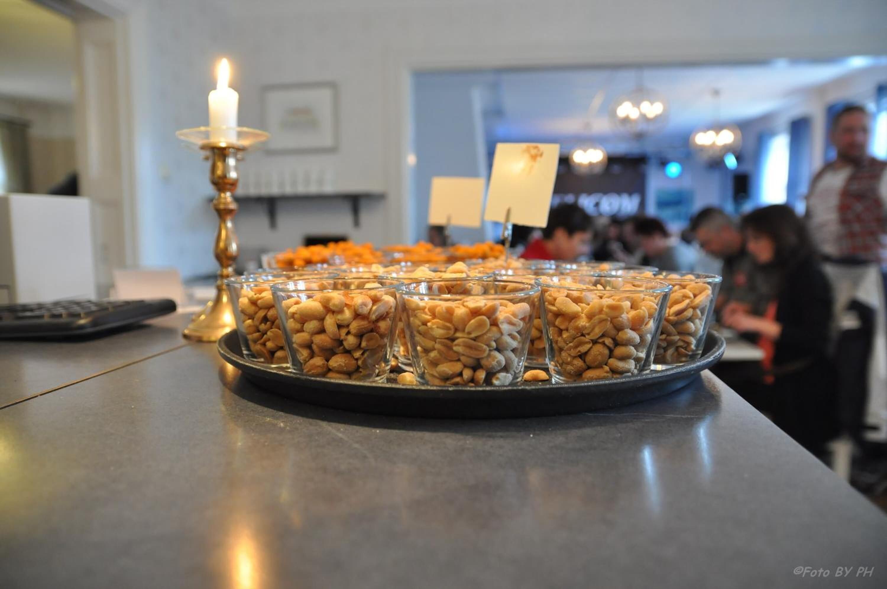 Una mesa de buffet con recipientes de vidrio llenos de nueces y una vela encendida.