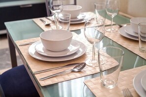 A dining table set with white bowls, plates, and cutlery, and a glass of water. - LuxApartments - Smolenskiy bulvar 7 (Moscow)