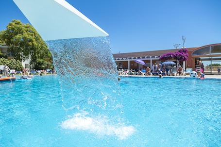 Una piscina al aire libre, sillones reclinables de piscina