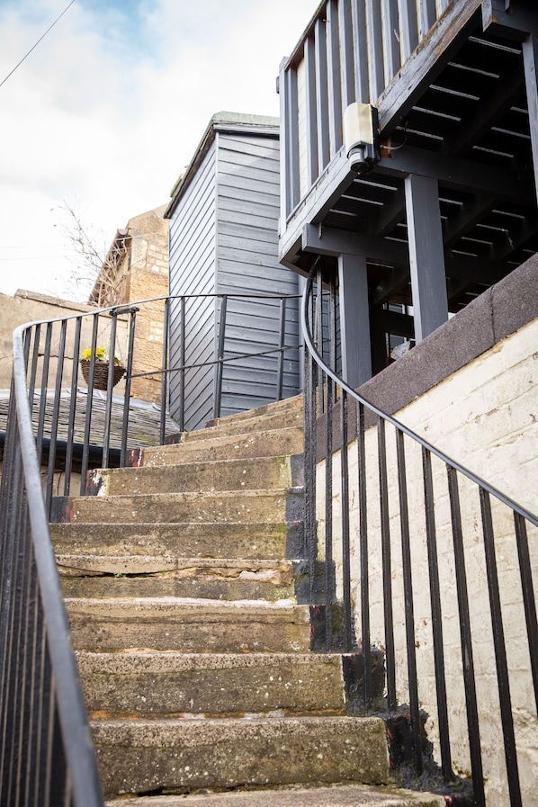 A set of stone steps leading up to a wooden deck with a metal railing.