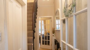 A hallway with a wooden staircase, a chandelier, and a door leading to another room. - Sandgate 2-bed Apartment in Ayr Central Location (Ayr)