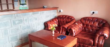 Un área de recepción con un mostrador de madera, un sofá de cuero y suelo de baldosas.