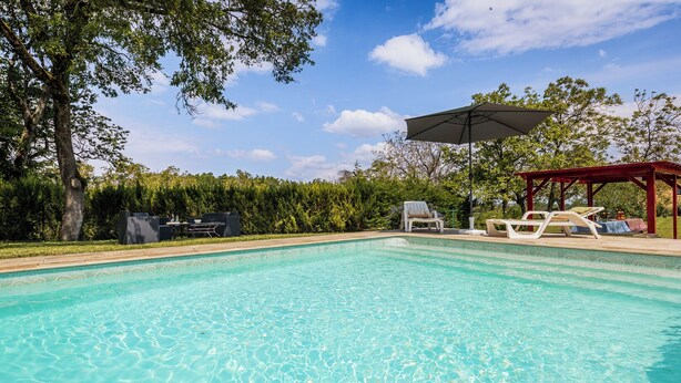 A clear swimming pool with lounge chairs and a covered area, surrounded by trees and a hedge. - Malsac is a spacious holiday home with large garden and private swimming pool (Florimont-Gaumier)