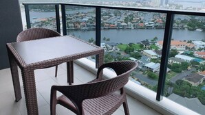 A balcony with wicker furniture, a view of a cityscape and a body of water. - Surferparadise Gem+parkingflexible Refund (Surfers Paradise)