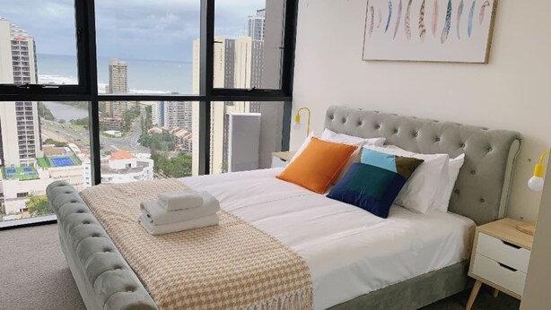 A hotel room with a large bed, a view of the city, and a painting on the wall. - Surferparadise Gem+parkingflexible Refund (Surfers Paradise)