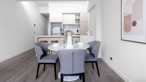A modern dining area with a round table, four grey chairs, and a white vase with a plant. - Delightful Townhouse Stay@moonee Ponds + Parking (Moonee Ponds)