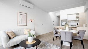 A modern living room with a sofa, coffee table, and dining area. - Delightful Townhouse Stay@moonee Ponds + Parking (Moonee Ponds)