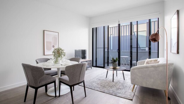 A modern living room with a round dining table, grey chairs, a grey sofa, and a large window with a view of the city. - Delightful Townhouse Stay@moonee Ponds + Parking (Moonee Ponds)