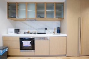Modern kitchen with microwave, coffee maker, dishwasher, and oven, plus ample storage space.