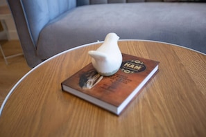 A book and a bird figurine sit atop a table, accompanied by a chair and a cabinet.