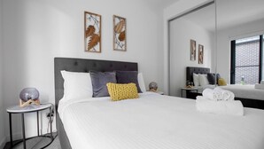 A modern hotel room with a large bed, a round side table, a mirror, and artwork on the walls. - Elegant Stylish Living@mooneeponds Wifi/parking (Moonee Ponds)