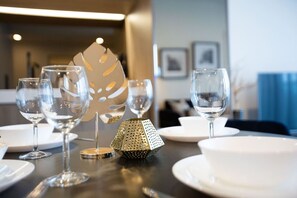 Een eettafel gedekt met wijnglazen, borden en een decoratief metalen object.