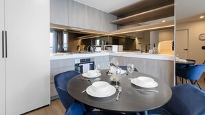Una cucina moderna con isola centrale, una zona pranzo con tavolo rotondo apparecchiato per quattro e un tavolo separato con due sedie.