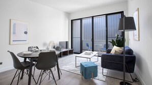 A modern living room with a dining area, a sofa, a coffee table, and a TV.
