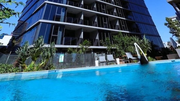 Ein modernes Hochhaus mit einem Pool davor.