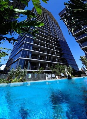 A modern high-rise building with a pool in front. - Stylist 2 Bedrooms Apartment With Pool/gym/parking (South Brisbane)
