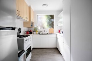 A modern kitchen with white cabinets, a stainless steel stove, and a window providing natural light.