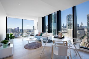 Un salon moderne avec vue sur la ville, comprenant un canapé, des fauteuils, une table à manger et une grande fenêtre.