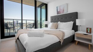 A modern bedroom with a large bed, a nightstand, and a view of the city through large windows. - Central Melbourne 2br2bt APT on Collins St+parking (Docklands)