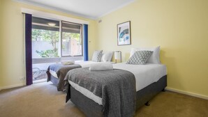 Ein Schlafzimmer mit zwei Betten, einem großen Fenster und einer Deckenleuchte.