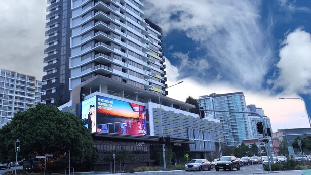 A high-rise hotel with multiple balconies, a prominent billboard advertising a hotel, and a clear sky with clouds. - Ultimate Prestige 2bed2bath Hamiltonapt (Hamilton)