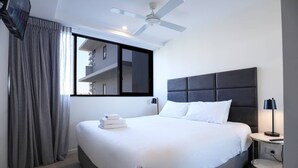 A modern hotel room with a large bed, a ceiling fan, a nightstand with a lamp, and a window with curtains. - Ultimate Prestige 2bed2bath Hamiltonapt (Hamilton)