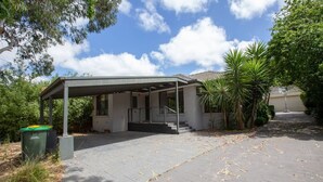 A covered outdoor area with a patio, a trash bin, and a staircase leading to a building. - Spacious 3bedrooms big House@mitcham (Mitcham)