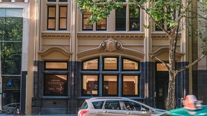 A building with large windows and a prominent entrance. - Modern Living@collins Centro Location 2BR (Melbourne)