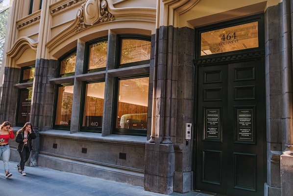 Un edificio con amplios ventanales y una puerta negra, con un letrero que indica el número 464 y Collins St.