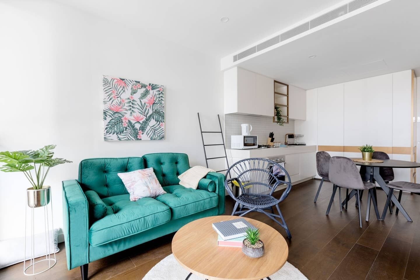 A modern living room with a teal sofa, a coffee table, and a dining area with a table and chairs.