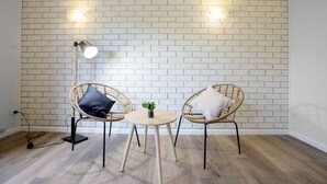 Una habitación con dos sillones de mimbre, una mesita redonda y una lámpara de pie.