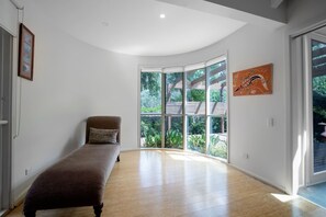 Quarto moderno com uma janela ampla, uma cama de solteiro e um quadro na parede.
