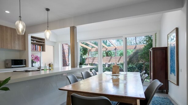 Un comedor moderno con una gran mesa de madera, sillas negras e iluminación colgante.