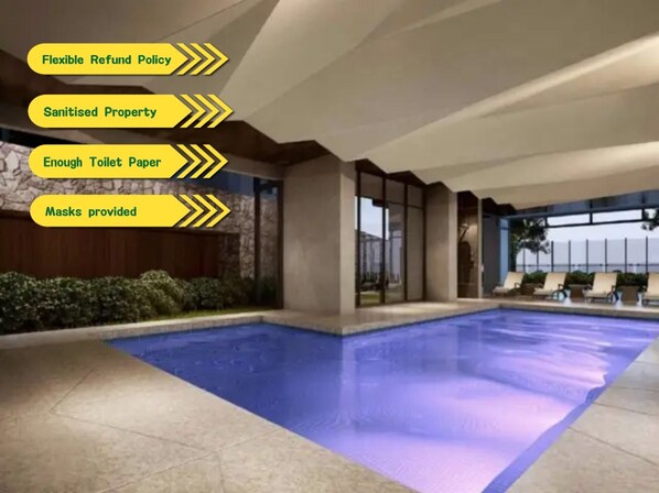 An indoor swimming pool with a clear view of the pool area, including the pool's edge and surrounding lounge chairs.