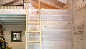 Un interior de fusta amb una escala, una cadira de cuir marró i un petit finestral.