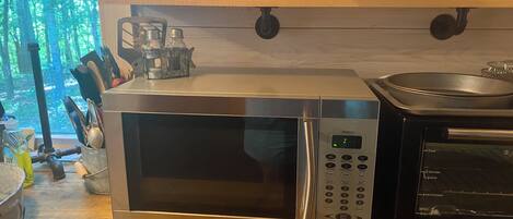 Une cuisine équipée d’un four à micro-ondes, d’un grille-pain et d’une bouilloire, le tout posé sur le plan de travail.