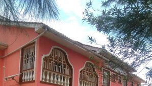 A pink building with large windows and a gated entrance.