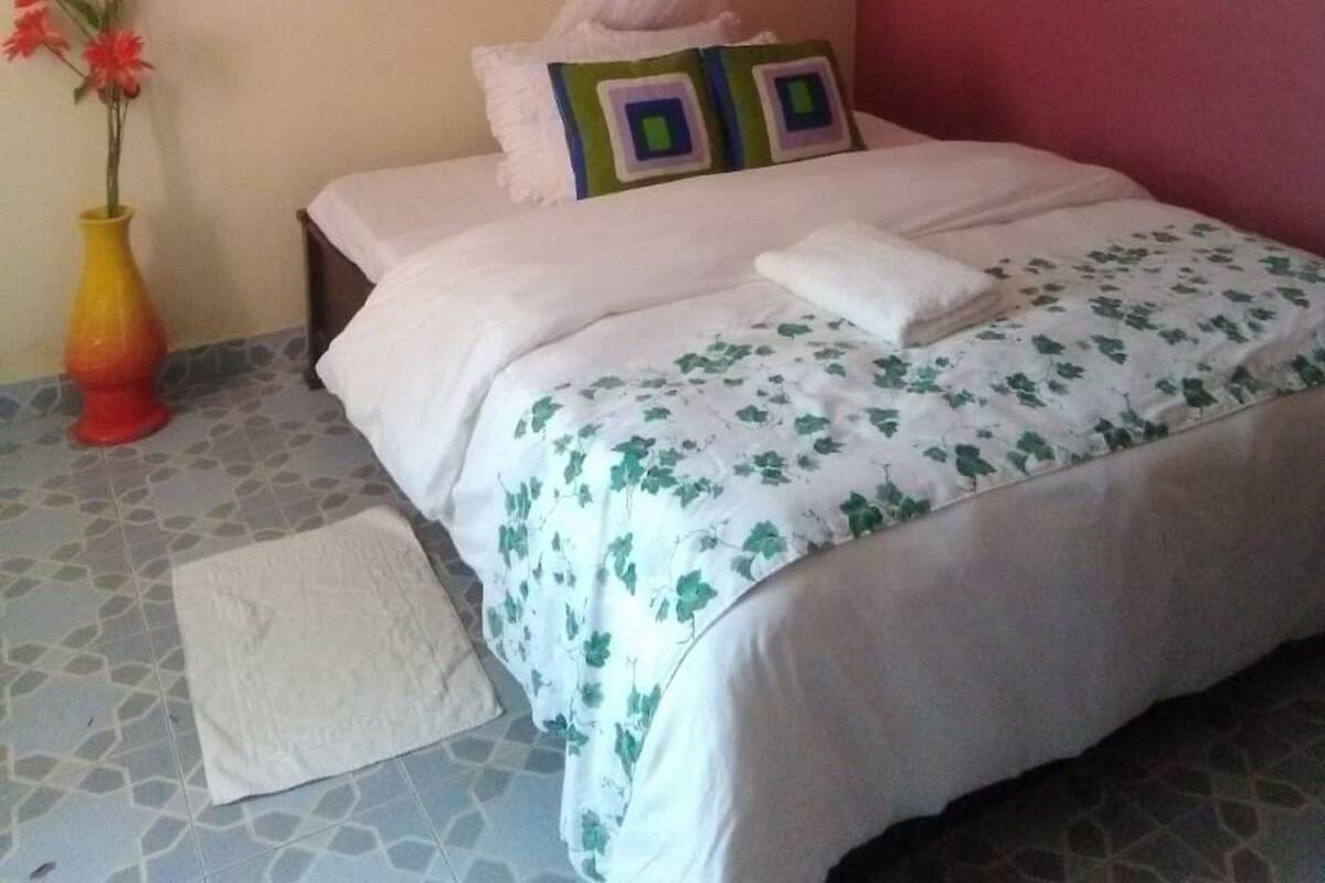 Ein Schlafzimmer mit einem Bett, einem Gemälde, einer Vase mit Blumen und einem Moskitonetz.