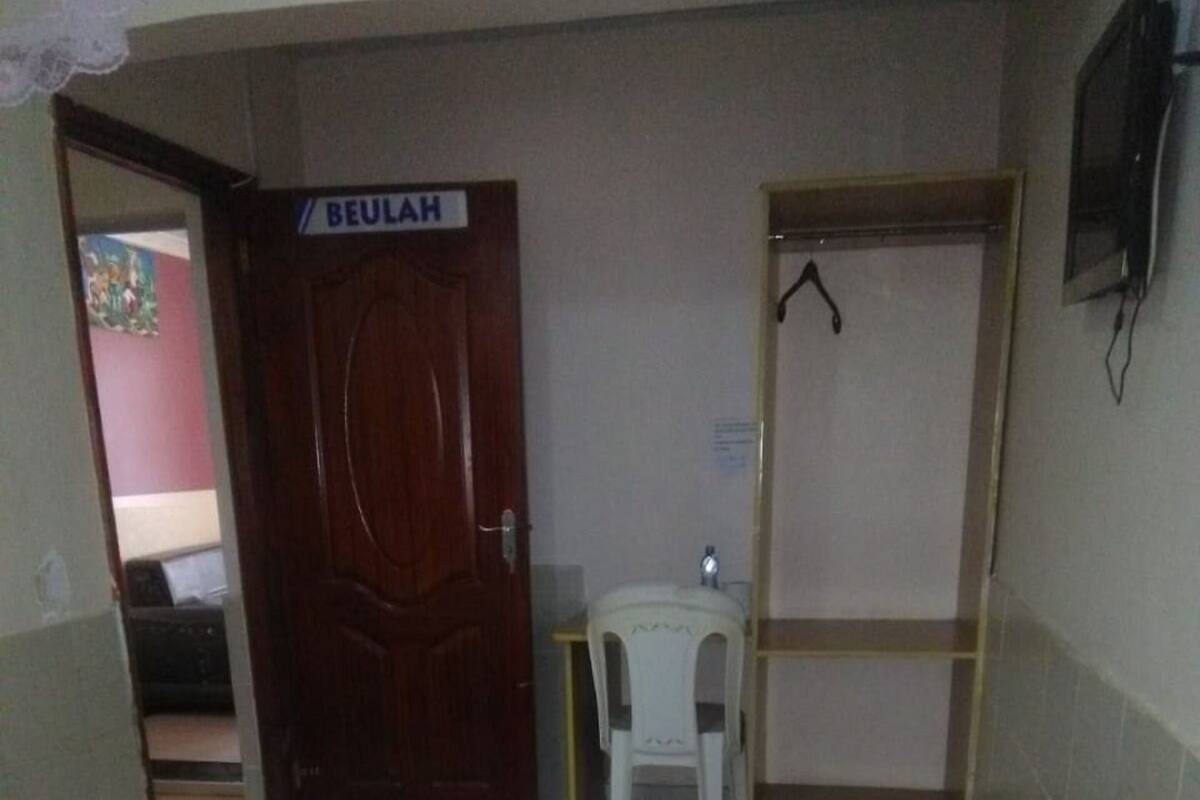 Ein Zimmer mit einem Bett, einem Schreibtisch, einem Stuhl und einer Tür mit der Aufschrift 'BEULAH'.