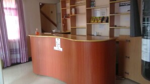 A reception desk with a wooden finish, a plant on top, and a bulletin board with notices.