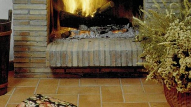 A fireplace with a fire, a lamp, and decorative items on the mantel.