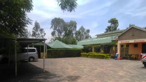 Un estacionamiento con aparcamiento techado, un edificio con el nombre 'Enigma Resort' y una estructura con techo verde.