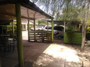 Un espace extérieur aménagé avec des tables et des chaises, une allée couverte et un véhicule stationné.