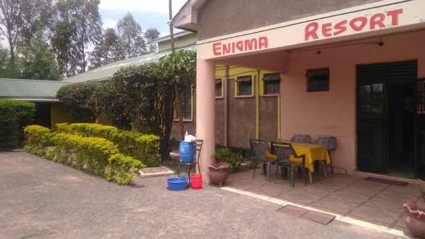 Un edificio con el letrero "ENIGMA RESORT", con área de estar al aire libre y plantas en macetas.