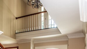 A spacious foyer with a wooden staircase, a large arched doorway, and a high ceiling with a chandelier. - Large Luxury Family Home Near Five Colleges. The TOP short term rental in area! (Hadley)
